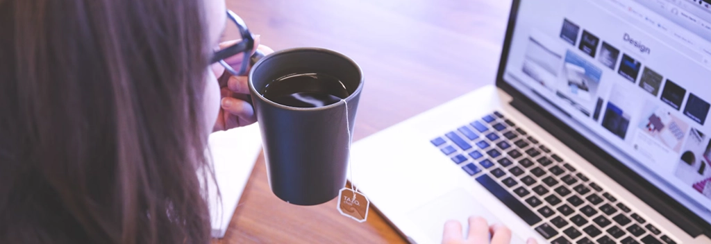 A woman sits with her laptop and a cup of tea navigating an easily used site