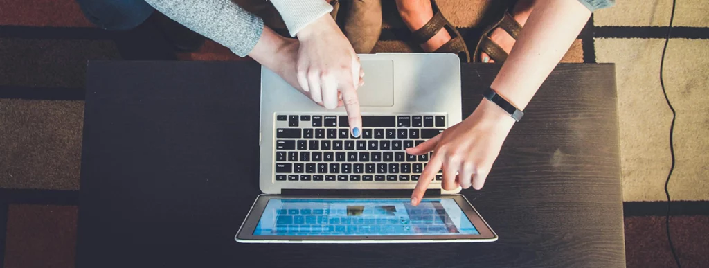 A group of people pointing at a laptop showing a website