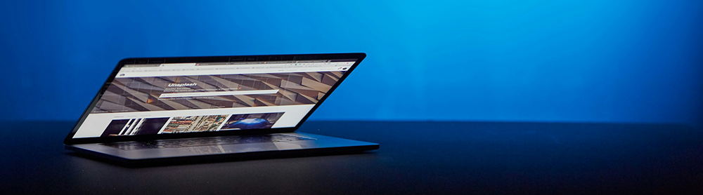 partially closed laptop on a black table with a blue neon background